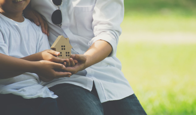 couple holding wooden house