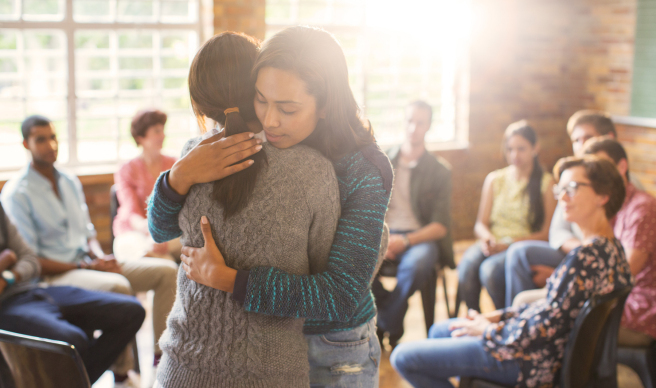 people hugging while group watches